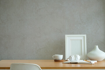 Home office concept. Empty  picture frame mockup, coffee cup and headphone on wooden table.