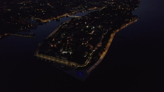 Aerial view of night cityscape with glowing lights reflecting on water, Zadar, Croatia.