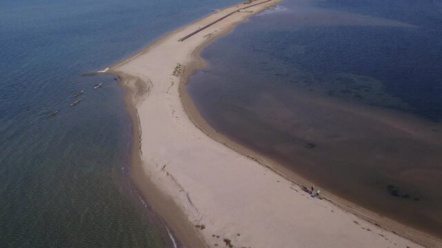 Aerial view of tranquil coastline with sandy beach, boat-filled harbour, and serene blue water, Nin, Croatia.