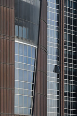 Obraz premium Architecture of a modern office building, construction background. Facade glass windows of a corporate center. Modern commercial buildings exterior.