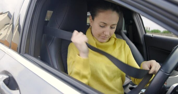 Woman fastening seat belt in the car before starting journey, close up view