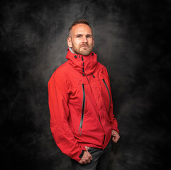 Handsome young man in a red sports jacket on a black background.