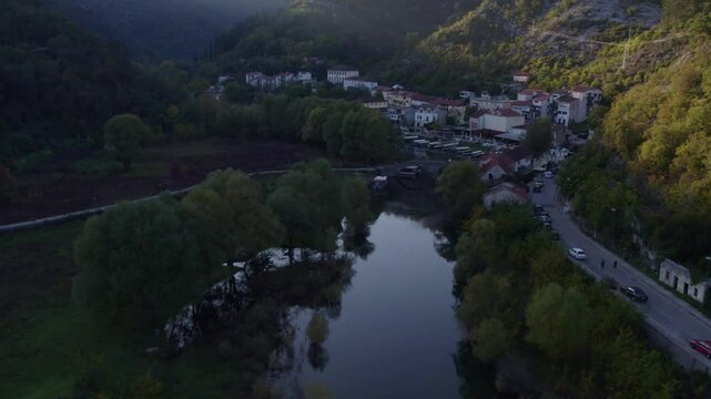 Aerial view of peaceful village with bridge and river at sunset, rijeka crnojevica, montenegro.