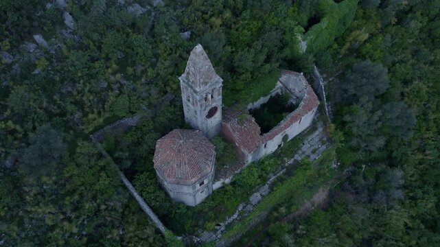Aerial view of abandoned church ruins in forested mountain landscape, Prcanj, Kotor Bay, Montenegro.