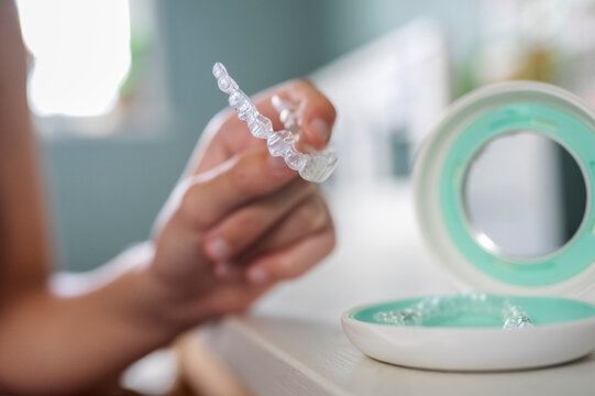 Close Up Of Teenage Girl Putting In Clear Dental Braces Or Aligners