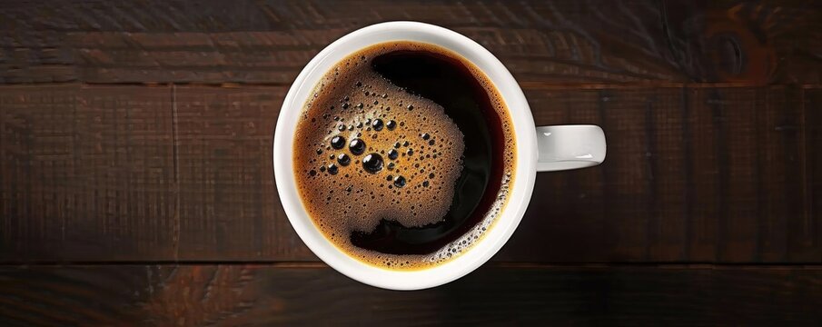 Top view of a steaming cup of black coffee on a wooden table, showcasing the rich texture and inviting aroma. Perfect for coffee lovers.