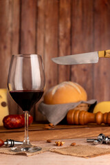 glass of red wine with wine bottle with cheese board country bread wooden board fresh grapes knife and cork opener and bottle
