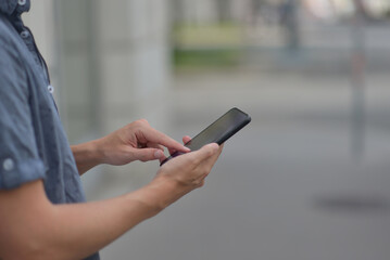 A man on the street using a smartphone. Mobile phone in hands close-up.