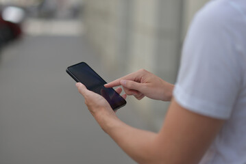 A man on the street using a smartphone. Mobile phone in hands close-up.