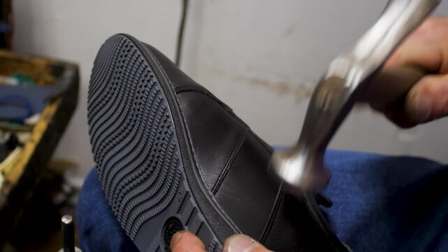 Bootmaker drive in nails in a shoe at the private workshop. Shoe making process