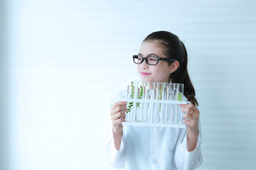 Cute girl wearing glasses holding test tubes holder and looking intently out the window.