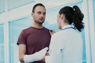Doctor comforting young male patient wearing arm cast