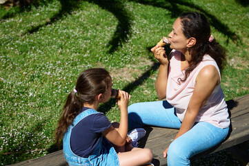 Mother and daughter enjoying ice cream on a sunny day in the park