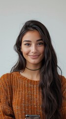 Fototapeta premium Smiling girl looking at camera holding smartphone on isolated background