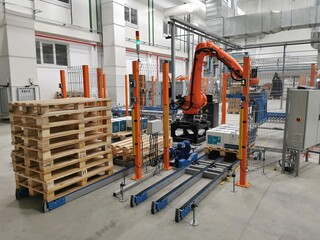 Robot palletizer orange KUKA robot kr180 stacks boxes on a pallet