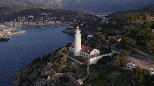 Aerial view of sunset over Balearic Sea with lighthouse and coastal town, Soller, Mallorca, Spain.