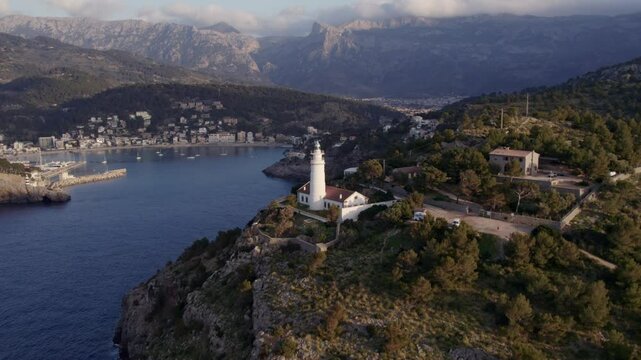 Aerial view of sunset over lighthouse, sea, cliff, and town in Mallorca, Spain.
