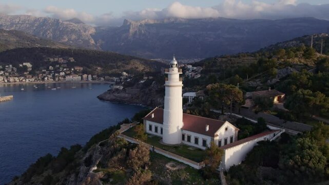 Aerial view of sunset over Balearic Sea with lighthouse, cliff, and mountains, Soller, Mallorca, Spain.