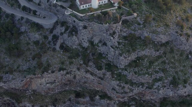 Aerial view of lighthouse, building, cliff, road, and trees at sunset, Soller, Mallorca, Spain.