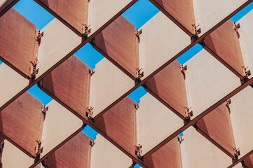 Geometric abstraction of metal narrow shields, brown, located diagonally, connected perpendicular to each other. Macro