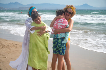 Grandmother and mother hugging and drying children with towels at the beach
