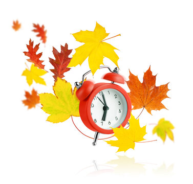 Red alarm clock and flying autumn leaves isolated on white background.