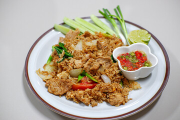 Thai style fried rice with pork, cucumber with chili in fish sauce in small cup on plate, Thai food.