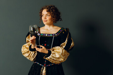 Young adult woman dressed in a medieval dress holding a glass of wine
