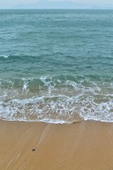 Close-up of soft waves sand beach and blue sea. Texture of water, white foam waves. Seascape, Sea background, Sea water with copy space, summer vacation concept. 