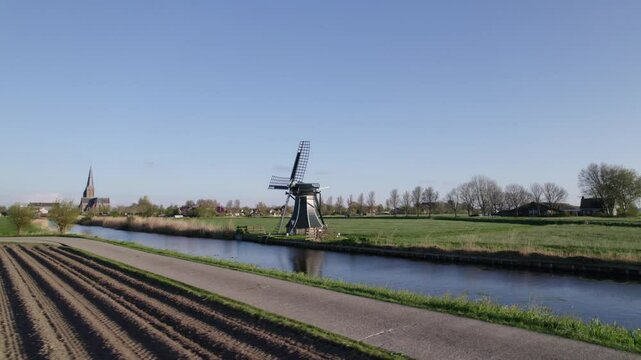Aerial view of picturesque countryside with windmill, church, meadow, and river, Workum, Friesland, Netherlands.
