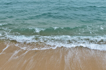 Close-up of soft waves sand beach and blue sea. Texture of water, white foam waves. Seascape, Sea background, Sea water with copy space, summer vacation concept. 
