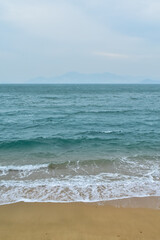 Close-up of soft waves sand beach and blue sea. Texture of water, white foam waves. Seascape, Sea background, Sea water with copy space, summer vacation concept. 
