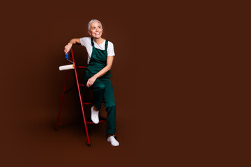 Photo of charming lovely senior woman wear uniform climb ladder empty space isolated on brown color background