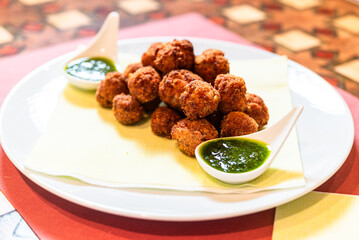 small fried meatballs with parsley pesto on white plate
