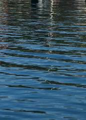 the water reflection of several boats in a sea port
