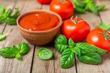 Tomato paste, sauce, ketchup in a bowl and cherry tomatoes with fresh basil leaves on a textured wooden background. Vitamins and detox diet. Vegetable and vegetarian food. Space for text. Copy space.