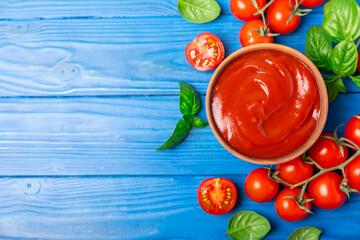 Tomato paste, sauce, ketchup in a bowl and cherry tomatoes with fresh basil leaves on a textured...