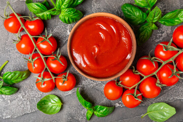Tomato paste, sauce, ketchup in a bowl and cherry tomatoes with fresh basil leaves on a textured...