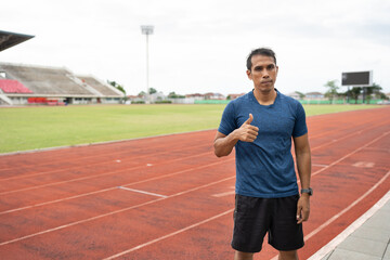 Portrait Thump up Mature fitness Asia man runner on racetrack	