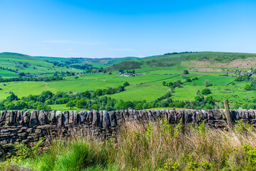 A view past a drystone wall towards farmland from the path leading to Luds Church in Staffordshire...