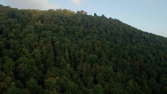 Aerial view of dense forest, castle, and mountain at sunrise light, Burg Teck, Baden-Wurttemberg, Germany.