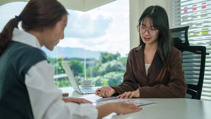 Two young female colleagues working together on new project at office.