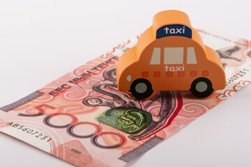 A symbolic taxi car and new banknotes in denominations of 5,000 Kazakhstani tenge