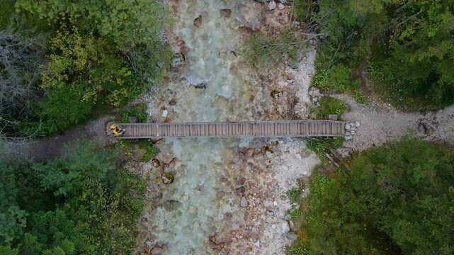 Aerial view of bridge, river, forest, and man walking in Triglavska Bistrica, Kranjska Gora, Slovenia.