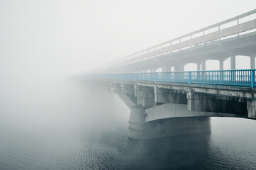Bridge to nowhere. Concrete bridge over a river covered in thick fog. Perspective view of a bridge...
