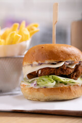 Delicious crispy chicken burger with fresh coleslaw and a soft brioche bun, served alongside golden french fries on a wooden tray. The setup is perfect for food photography showcasing fast food