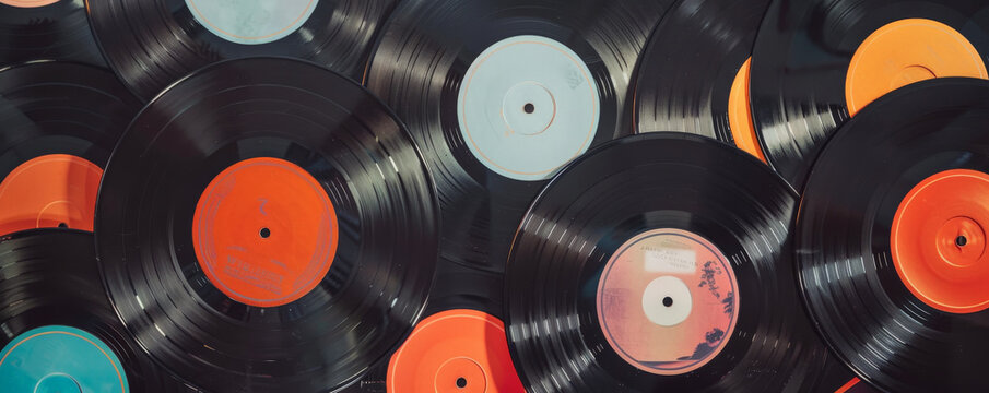 Overhead top down view of a collection of different vinyl records displayed in a vintage record store setting. The album covers feature various genres and eras, creating a nostalgic and eclectic