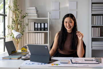 A woman is sitting at a desk with a laptop and a tablet