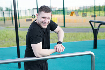 Caucasian male athlete doing pull-ups on the horizontal bar outdoors in a summer park