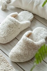 Pair of stylish soft slippers on white wooden background